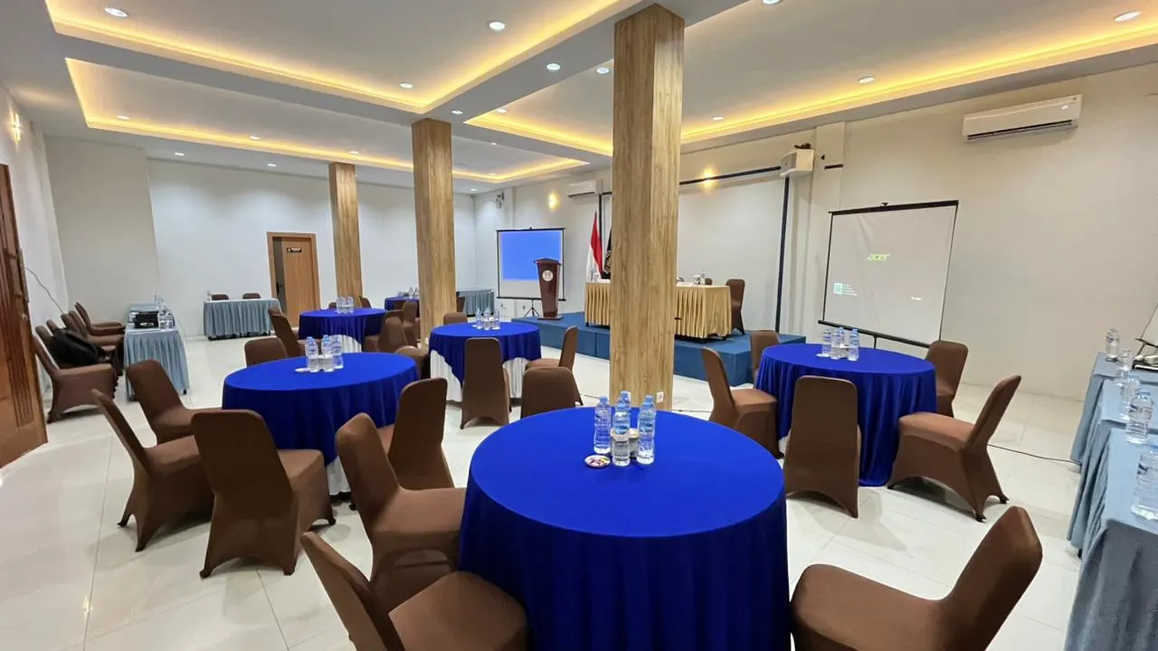 Meeting room Hotel MK Mulia dengan meja bundar dan layar proyektor